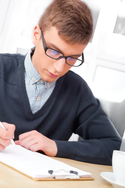 Gymnasiet - ung manlig student skriva anteckningar i klassrummet — Stockfoto