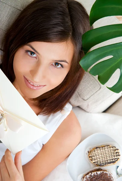 Delighted woman reading a greeting card sitting on the sofa at h — Stock Photo, Image