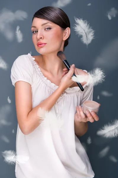 Portret van een mooie vrouw toepassing van make-up met borstel op haar — Stockfoto