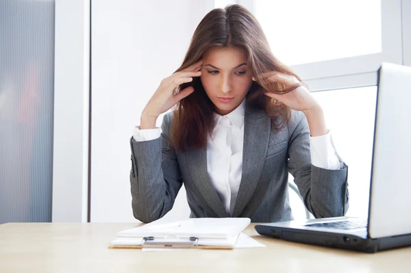 Trött business kvinna som arbetar på hennes arbetsyta — Stockfoto