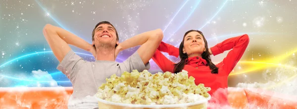 Junges glückliches Paar vor dem Fernseher zu Hause mit offenen Armen und daydre — Stockfoto