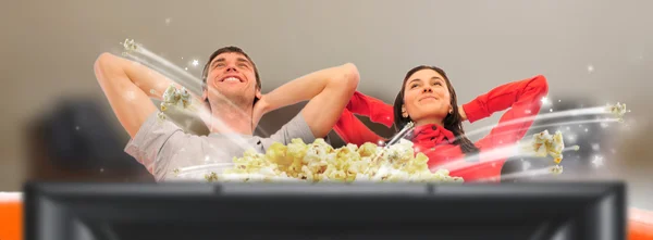 Jovem casal feliz assistindo TV em casa com os braços abertos e daydre — Fotografia de Stock