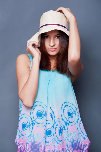 Mujer segura con los brazos cerca de la cabeza sosteniendo el sombrero contra un bl —  Fotos de Stock
