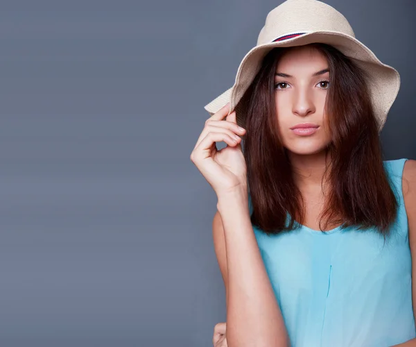 Vertrouwen vrouw met armen in de buurt van haar hoofd bedrijf hoed tegen een bl — Stockfoto