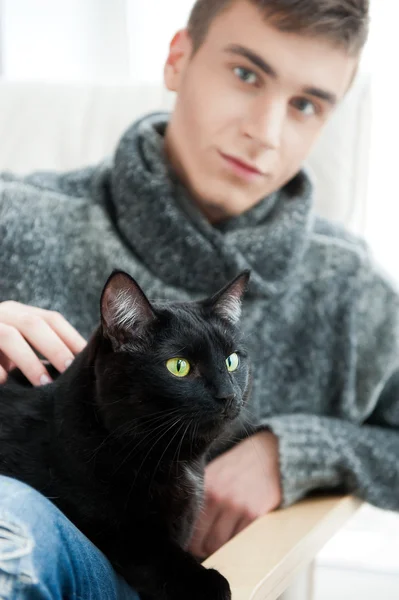 Расслабленный мужчина сидит на кресле и ласкает кошку — стоковое фото