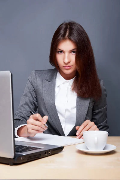 Une femme assez concentrée qui travaille avec son ordinateur portable et ses papiers . — Photo