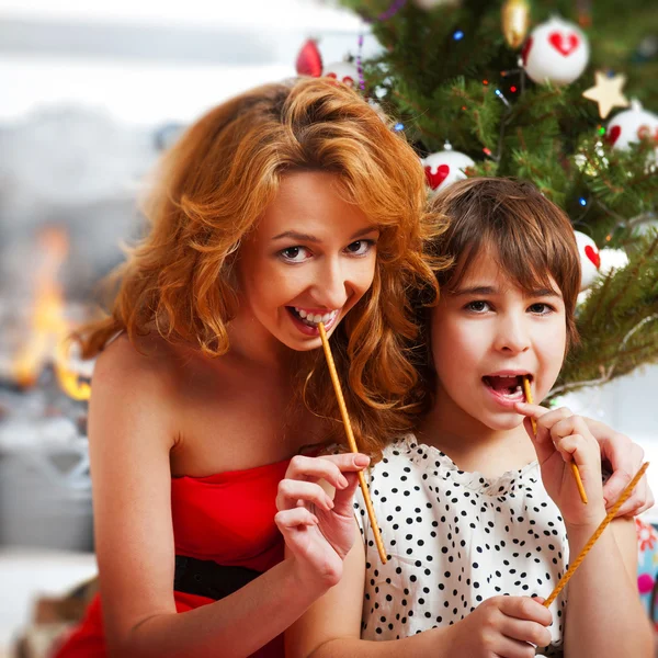 Madre y su hija sentadas juntas cerca del árbol de Navidad — Foto de Stock