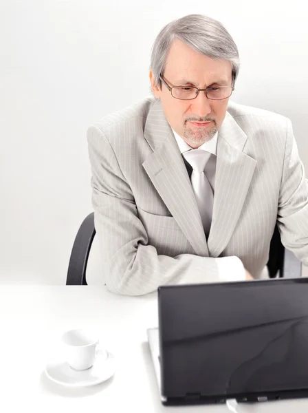 Portret van een oudere zakenman met een computer en een kopje. — Stockfoto
