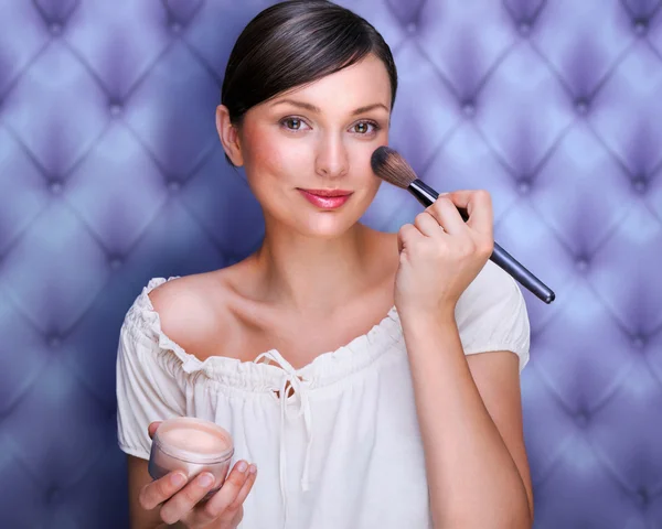 Portrait of attractive young adult woman applying blusher agains — Stock Photo, Image