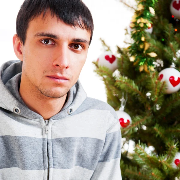 若い穏やかなクリスマス ツリーの前に座っている男 — ストック写真