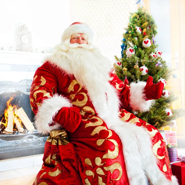 Санта сидит у елки, у камина и смотрит в окно. — стоковое фото
