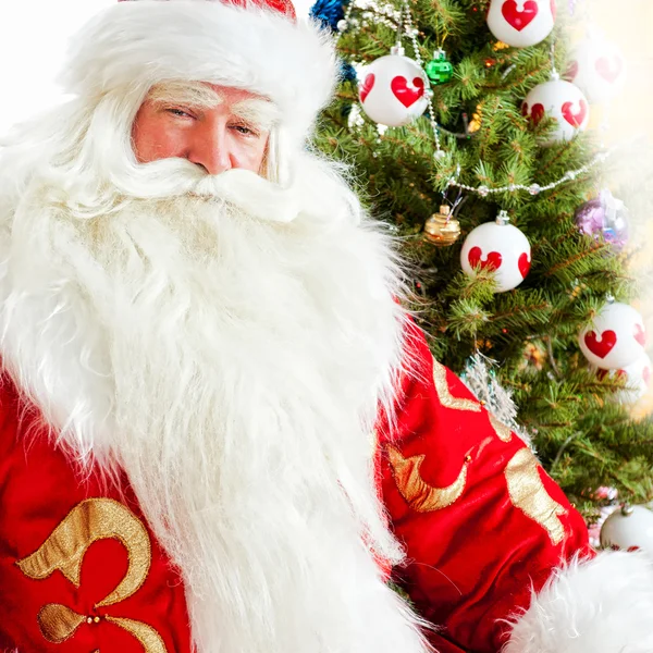 Santa siedzi na Boże Narodzenie drzewo, kominka i patrząc na ca — Zdjęcie stockowe