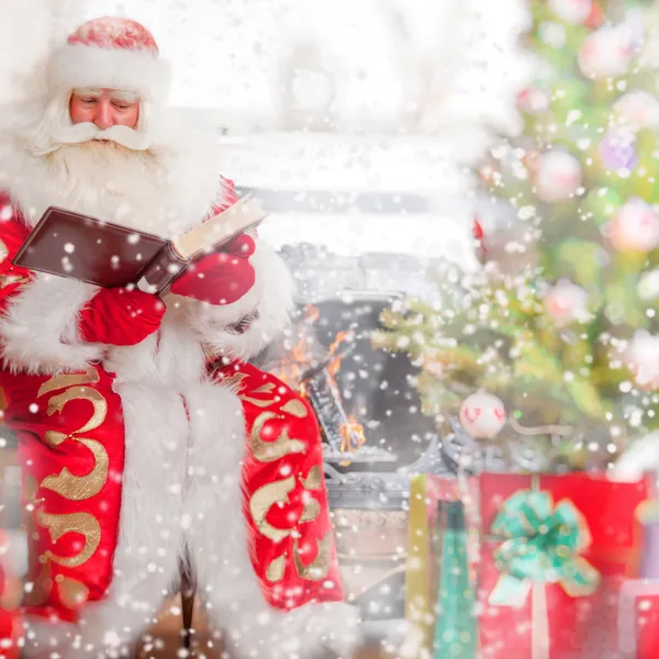 Weihnachtsmann sitzt am Weihnachtsbaum, am Kamin und liest — Stockfoto