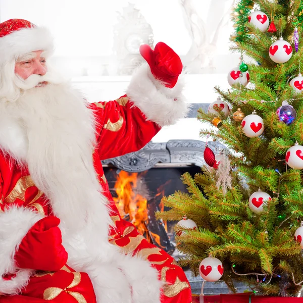 Санта сидит у елки, у камина и смотрит — стоковое фото