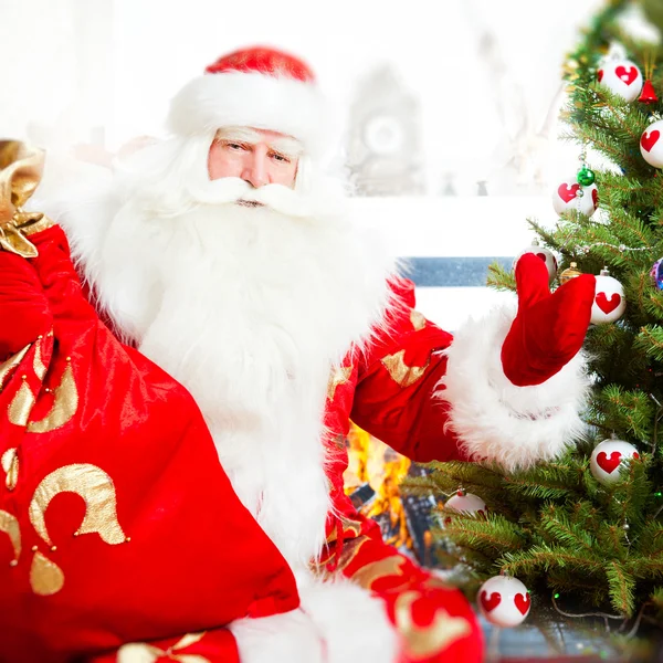Santa na vánoční stromeček, poblíž ohniště a hledá — Stock fotografie