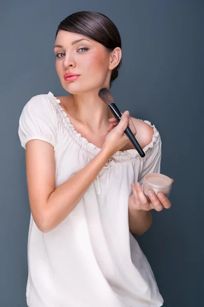 Portret van een mooie vrouw met make-up borstel in de buurt van haar gezicht lo — Stockfoto