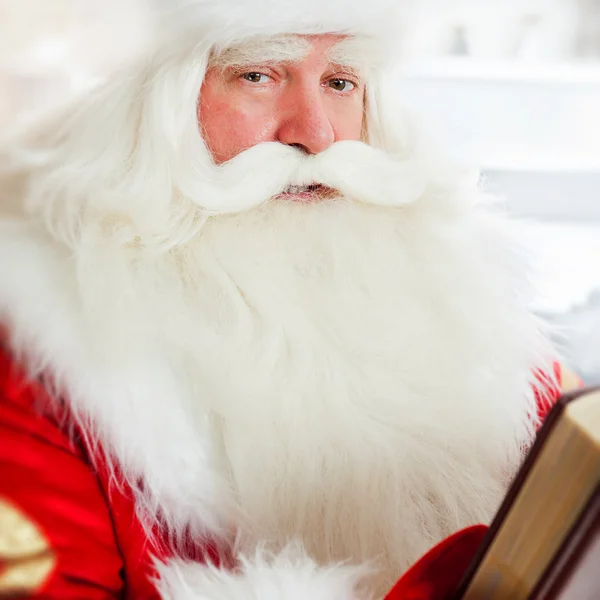 Santa sitta hemma och läsa en bok. inomhus — Stockfoto