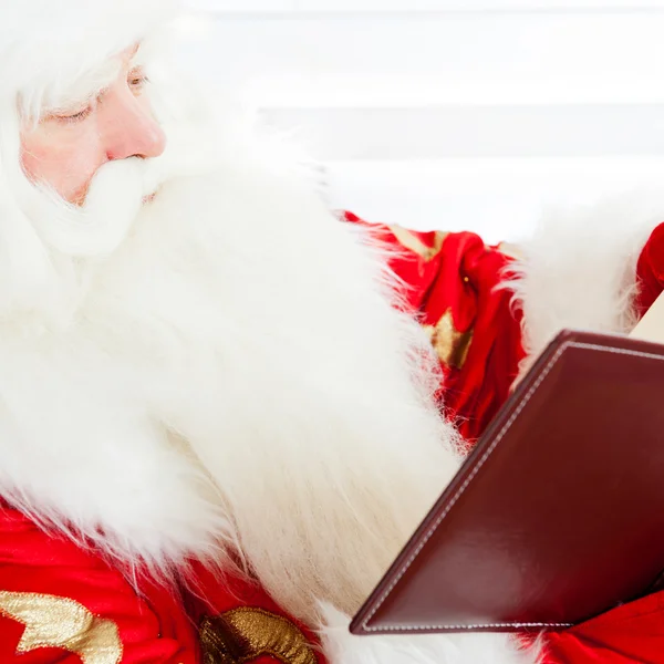 Evde oturan ve bir kitap okuma Noel Baba. kapalı — Stok fotoğraf