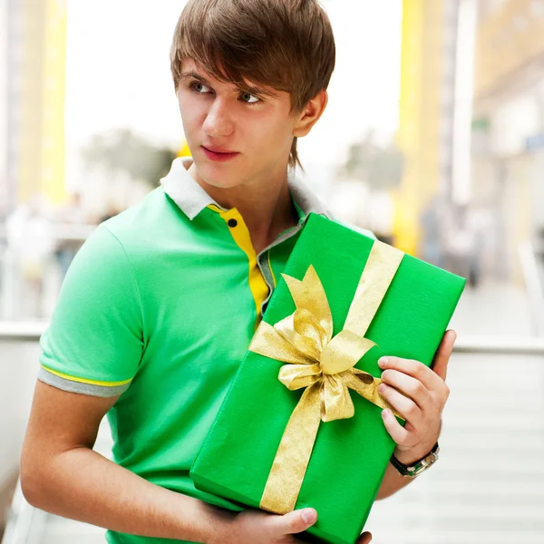 Retrato de hombre joven dentro del centro comercial con caja de regalo standin — Foto de Stock