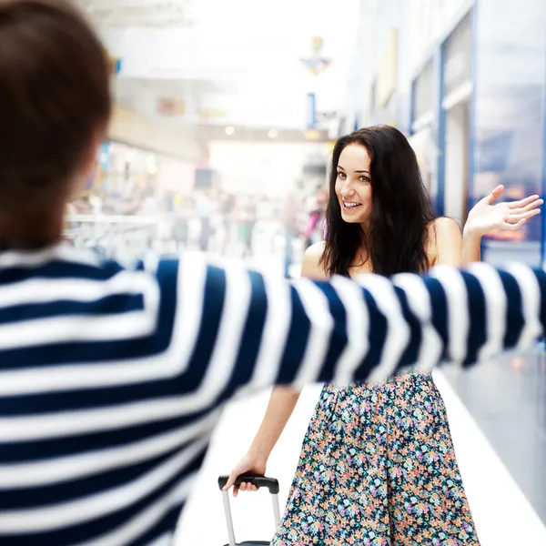 Young man meeting his girlfriend with opened arms at airport arr — Stock Photo, Image