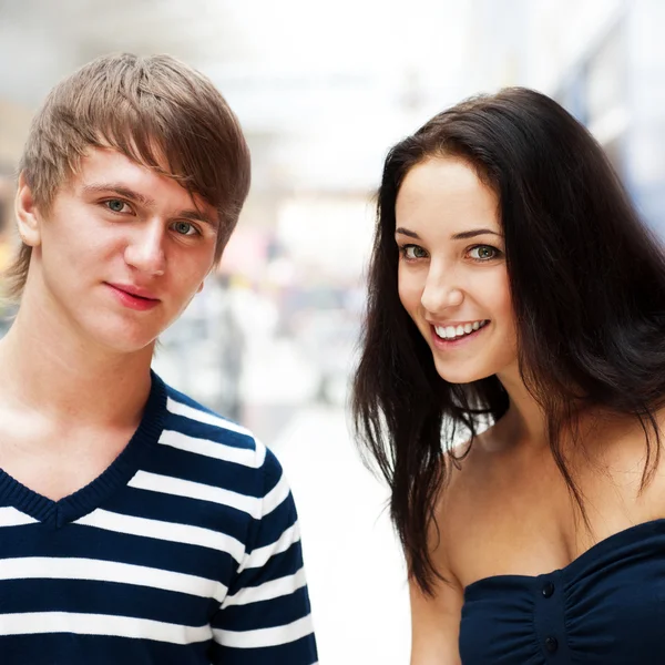 Portrait of young couple embracing at shopping mall and looking — Stock Photo, Image