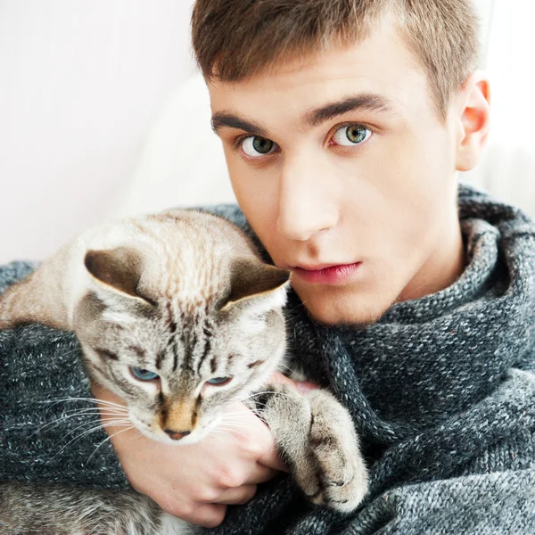Koltuk holding ve evcil hayvan kedi sevişme üzerinde oturan rahat adam — Stok fotoğraf