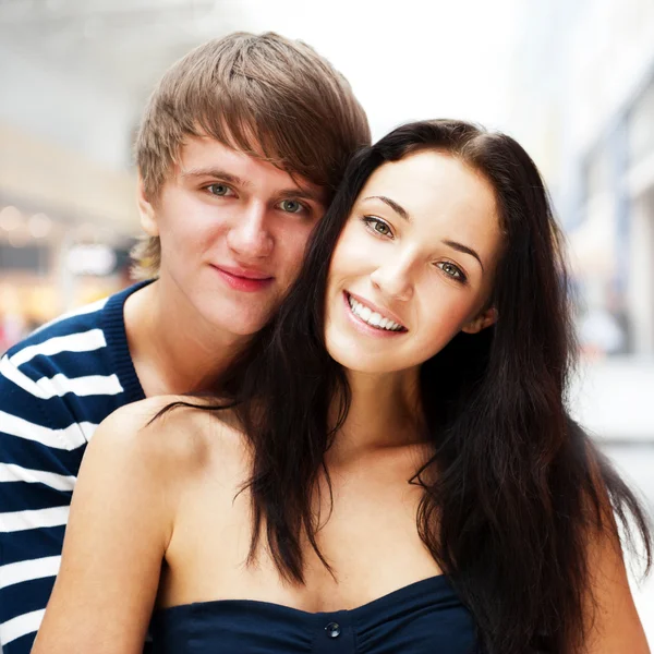 Portrait of young couple embracing at shopping mall and looking Stock Photo