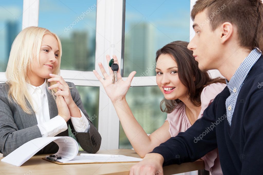 Portrait of a happy young couple talking with agent while signin