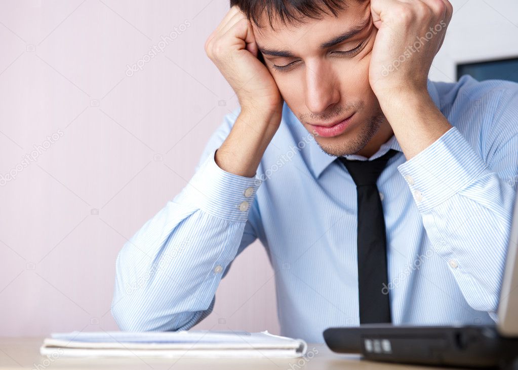 Tired businessman sleeping at his desk in the office with both a