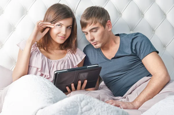 Νεαρό ζευγάρι ζωντανή χρήση tablet pc στο κρεβάτι τους και ονειροπόληση — Φωτογραφία Αρχείου