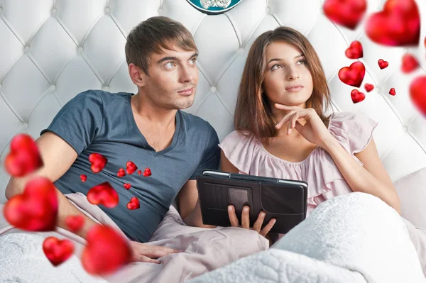 Jovem casal animado usando tablet PC em sua cama e sonhando acordado — Fotografia de Stock