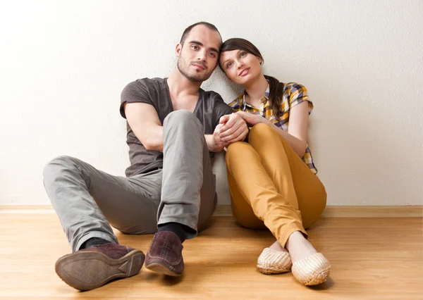 Attractive young adult couple sitting close on floor in home smi — Stock Photo, Image
