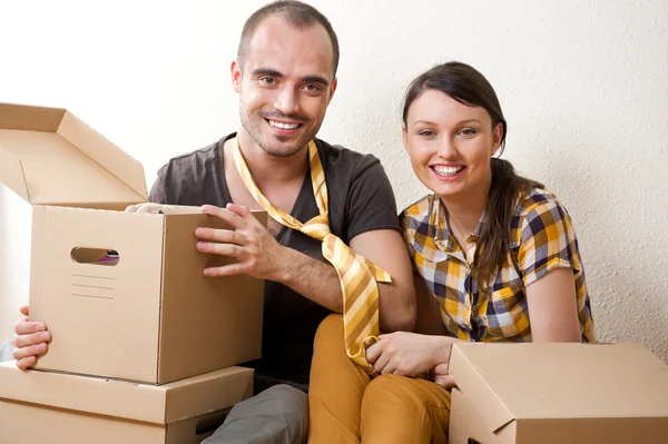 Young Couple with boxes in the new apartment sitting on floor an — Stock Photo, Image