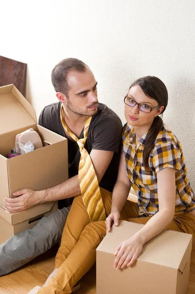 หนุ่มสาวคู่กับกล่องในอพาร์ทเม้นท์ใหม่นั่งอยู่บนพื้น — ภาพถ่ายสต็อก