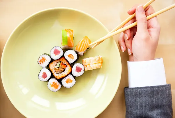 Vista superior de la joven mujer de negocios que lleva traje con sushi stic — Foto de Stock