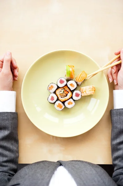 Visão superior da jovem mulher de negócios vestindo terno segurando sushi stic — Fotografia de Stock