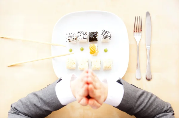 Stock image Top view of sushi set on white plate, sticks and fork and knife