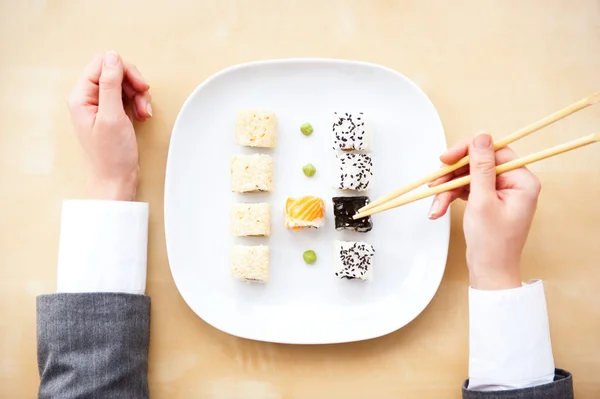 Bovenaanzicht van jonge zakenvrouw dragen pak houden sushi stic — Stockfoto