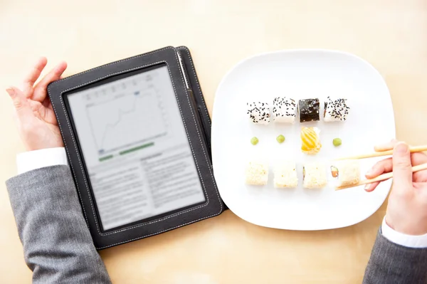 Pretty woman holding sushi with chopsticks and reading news usin — Stock Photo, Image