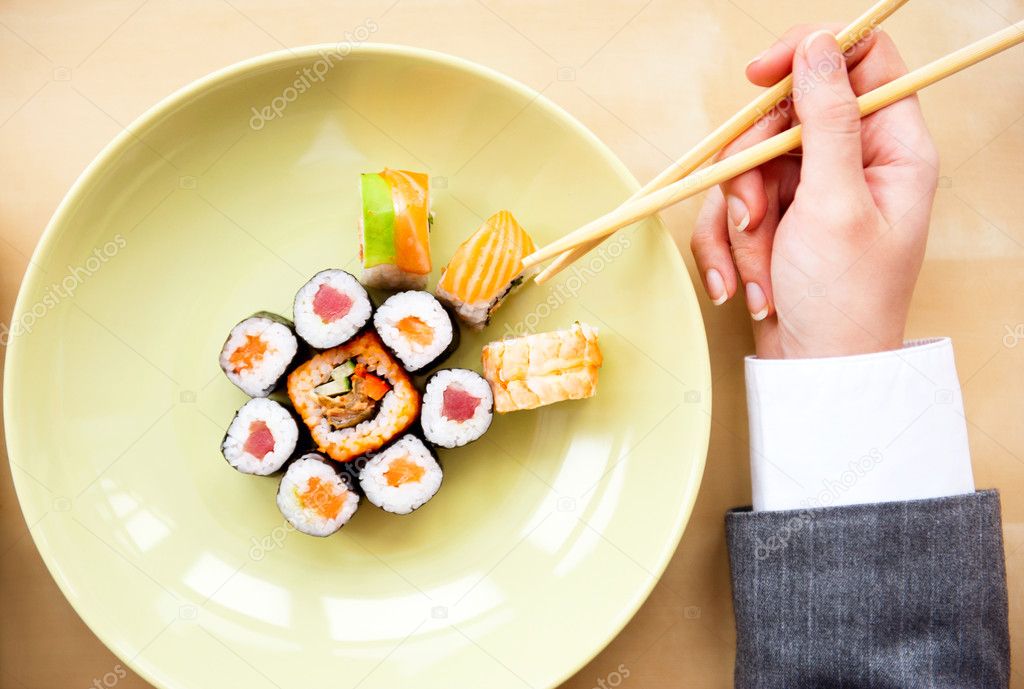 Top view of young business woman wearing suit holding sushi stic