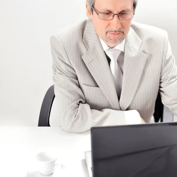 Portret van een oudere zakenman met een computer en een kopje. — Stockfoto
