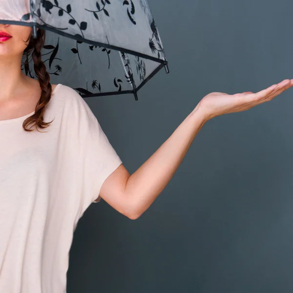 Joven mujer de moda sosteniendo paraguas de pie contra gris b — Foto de Stock
