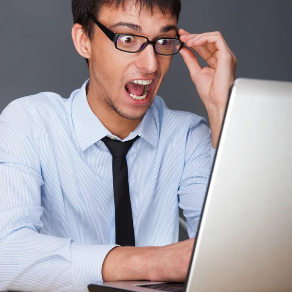 Jeune homme séduisant travaillant avec un ordinateur portable à son bureau. Il est... — Photo