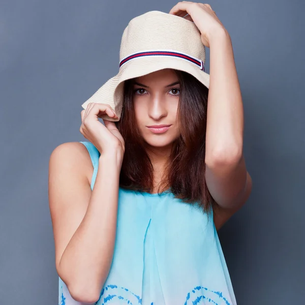 Mujer segura con los brazos cerca de la cabeza sosteniendo el sombrero contra un bl —  Fotos de Stock