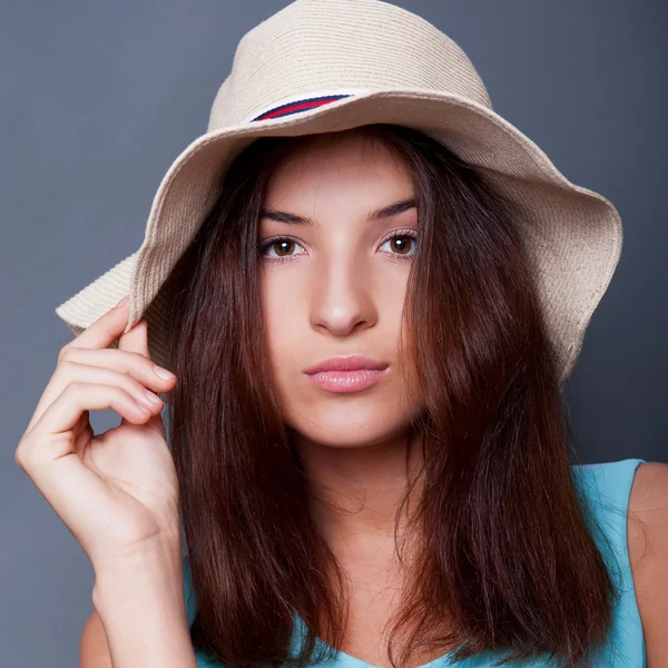 Confident woman with arms near her head holding hat against a bl — Stock Photo, Image