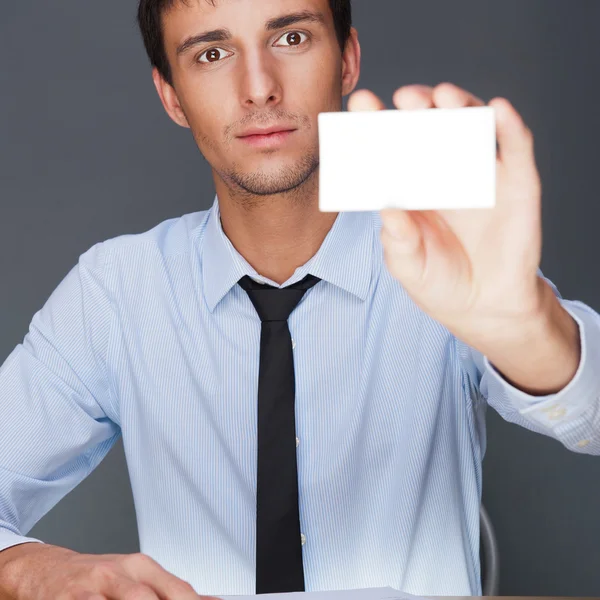 Business man handing a blank business card over grey background — Stock Photo, Image