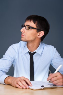 Portrait of an adult business man sitting in the office and signing documen clipart