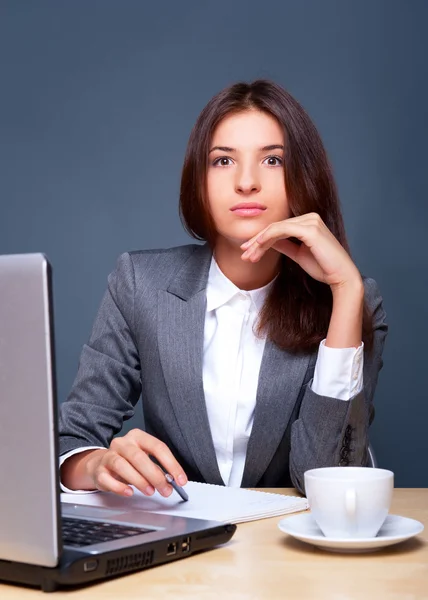 A pretty concentrated woman working with her laptop and papers. Sitting at — Stock Photo, Image