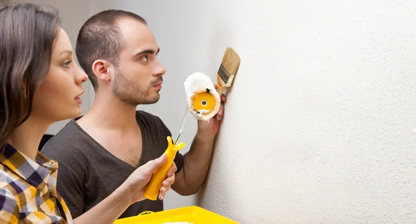 Happy smiling couple painting interior wall of home and having fun — Stock Photo, Image