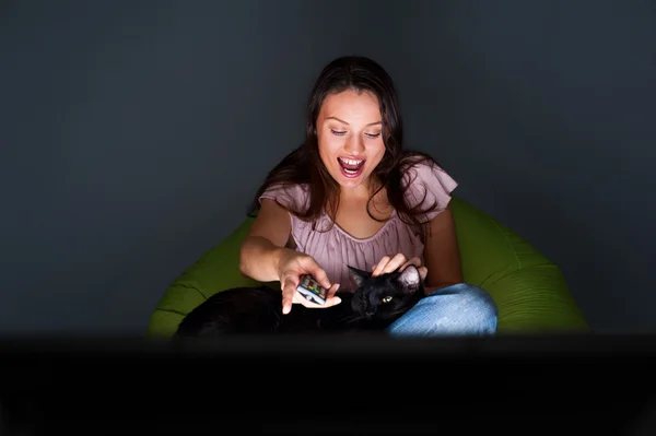 Happy young woman swapping the TV channels , relaxed on the beanbag couch. — Stock Photo, Image